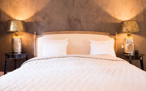 a bedroom with a white bed with two lamps at Suitehotel Posthoorn in Monnickendam