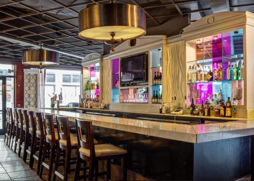 a bar with a row of chairs and bottles of alcohol at Hotel Providence, Trademark Collection by Wyndham in Providence