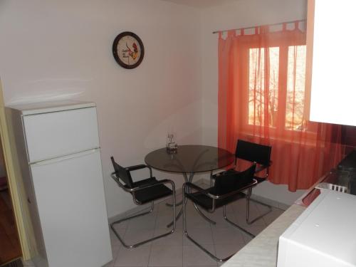 einen Tisch und Stühle in einer Küche mit einer Uhr an der Wand in der Unterkunft Apartman Zlatko in Zadar