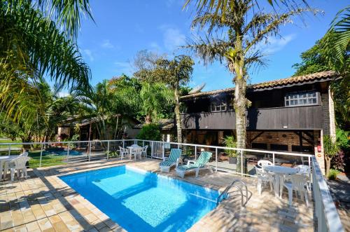 a house with a swimming pool and palm trees at Chalés do Holandês Eco Pousada in Bombinhas