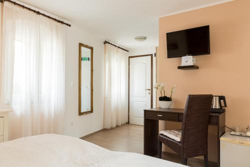 a bedroom with a desk and a television on a wall at Guesthouse Imperator in Split