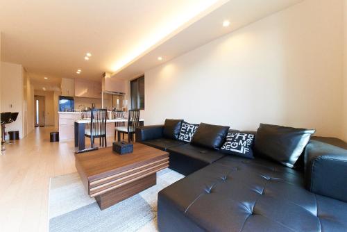 a living room with a black leather couch and a table at Kyoto river side modern House in Kyoto
