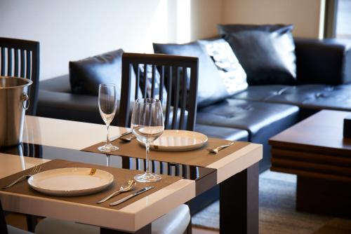 a dining table with two wine glasses and a couch at Kyoto river side modern House in Kyoto