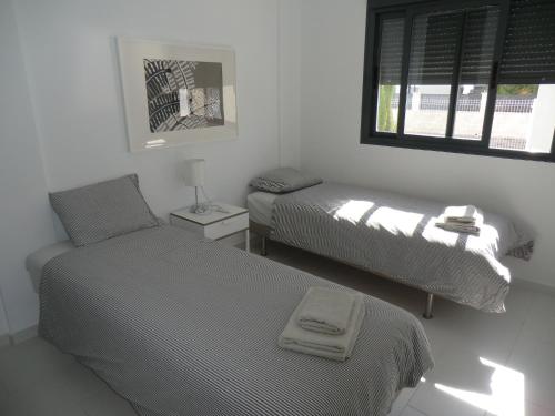 a bedroom with two beds and a chair and a window at Casas Holiday - Oasis Beach in Playas de Orihuela