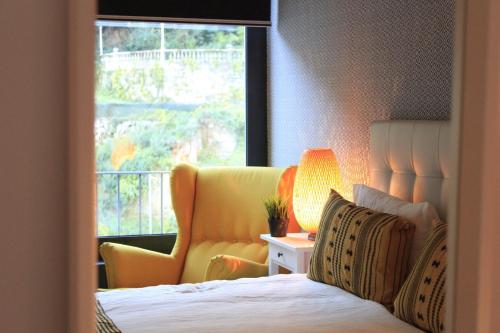 ジェレスにあるCaldas do Gerês Apartmentのベッドルーム1室(ベッド1台、黄色い椅子、窓付)