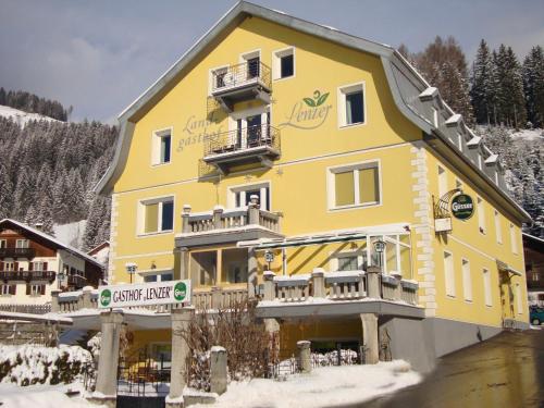 un grand bâtiment jaune avec de la neige au sol dans l'établissement Landgasthof Lenzer, à Strassen