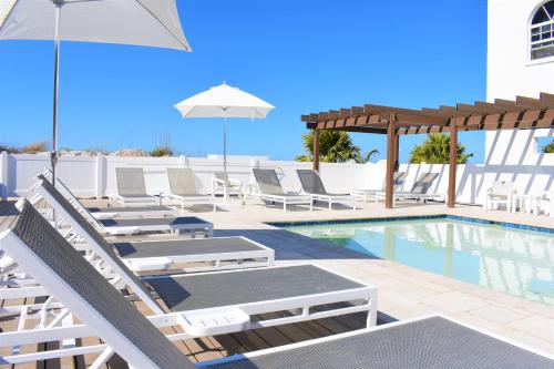 a swimming pool with lounge chairs and an umbrella at Barefoot Beach Club in St Pete Beach
