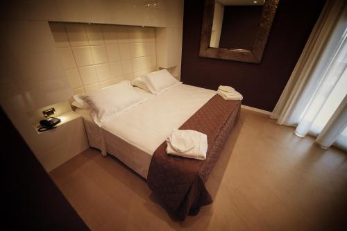 a small bedroom with a bed and a mirror at Gran Paradiso Hotel Spa in San Giovanni Rotondo
