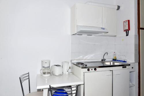 a white kitchen with a sink and a stove at Anna Studios in Pythagoreio