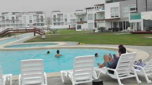 Condominio Las Terrazas في آسيا: مجموعة أشخاص جالسين على كراسي في مسبح