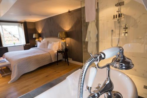 a bathroom with a bed and a tub and a sink at Suitehotel Posthoorn in Monnickendam