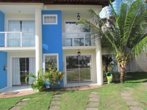 une maison bleue avec un palmier en face dans l'établissement Ap (Flat) Taperapuã Porto Seguro, à Porto Seguro