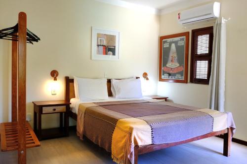 a hotel room with a bed and a night stand at Hotel e Pousada La Dolce Vita in Canoa Quebrada