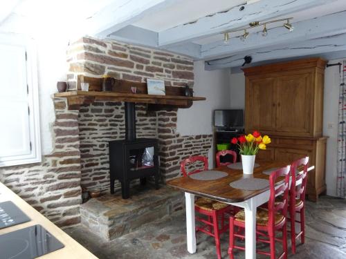 - une cuisine avec une table et une cheminée en briques dans l'établissement La Cour du Bourg, à Saint-Jean-des-Champs