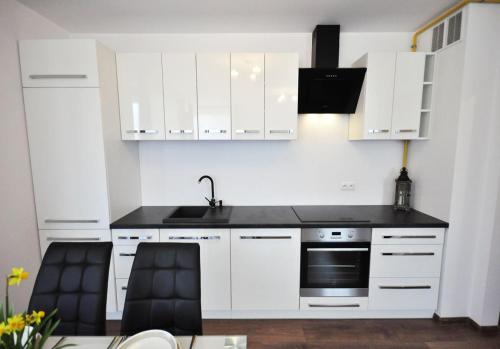a kitchen with white cabinets and a sink and a stove at Apartament Parkowy in Rabka-Zdrój