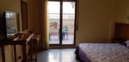 a bedroom with a bed and a door to a balcony at Hotel Reina Isabel in Lleida