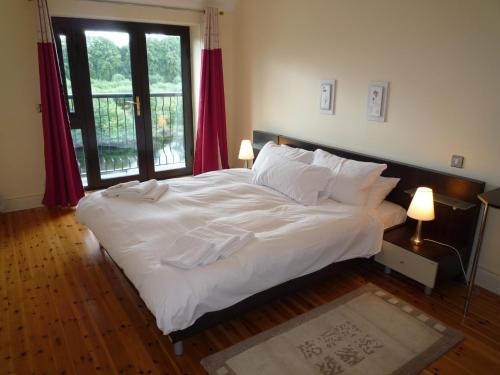 ein Schlafzimmer mit einem großen Bett mit weißer Bettwäsche und Kissen in der Unterkunft Grove Lodge Holiday Homes in Killorglin