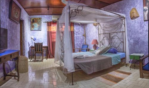 um quarto com uma cama de dossel num quarto roxo em Le Karite Bleu em Ouagadougou