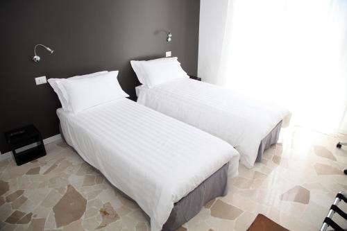 2 camas en una habitación de hotel con sábanas blancas en Torregiardino, en Abbiategrasso
