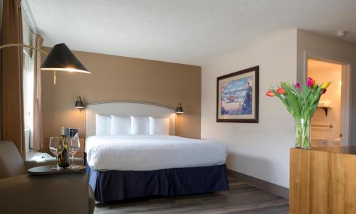 a hotel room with a bed and a vase of flowers at Hotel Focus SFO in South San Francisco