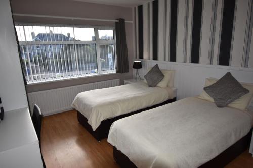 a hotel room with two beds and a window at Aaranmore Lodge Guest House in Portrush