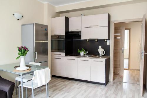 グダニスクにあるHello Apartments Ogarnaの白いキャビネットとテーブル付きのキッチンが備わります。