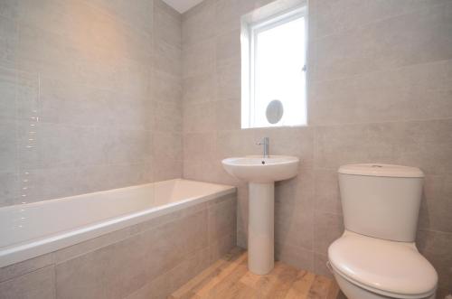 a bathroom with a toilet and a sink and a bath tub at Fossgate Luxury Duplex City Centre Apartment in York