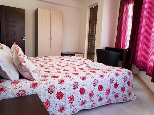 a bedroom with a bed with a red and white blanket at Family Aparthotel Vintegra in Burgas