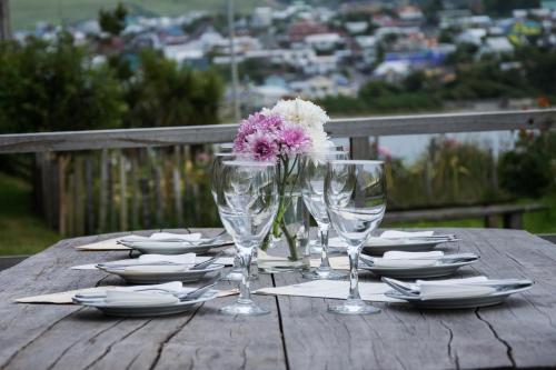 a wooden table with glasses and plates and a flower on it at Hostal Mundo Nuevo in Ancud