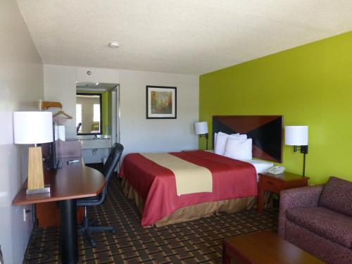 a hotel room with a bed and a desk and a chair at Coach Inn - Summerville in Summerville