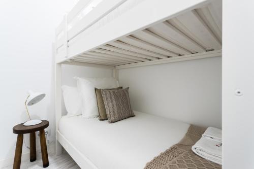 um pequeno quarto branco com uma cama e um banco em FLH Graça Cozy Flat em Lisboa