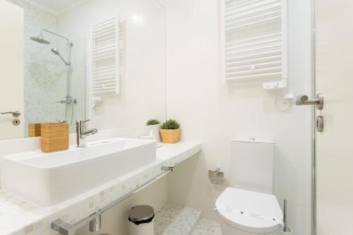 uma casa de banho branca com um lavatório e um WC em FLH Graça Cozy Flat em Lisboa