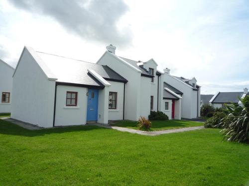 a row of white houses with a green yard at Achill Sound Holiday Village No 9 by Trident Holiday Homes in Achill Sound