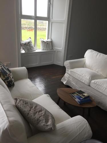 a living room with two white couches and a window at Berry Lodge Country House in Spanish Point