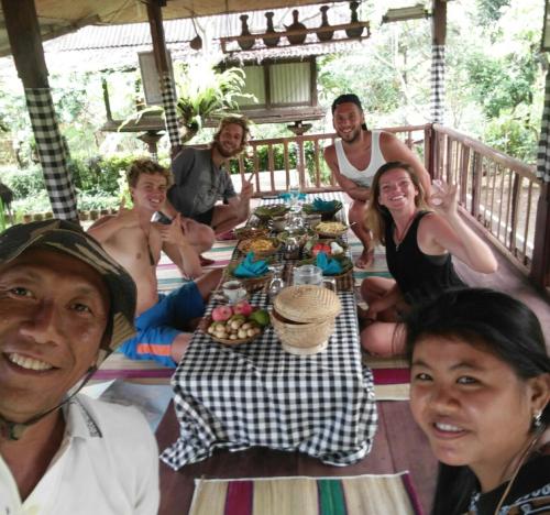 a group of people sitting around a table with food at ESA di Kubu Homestay in Singaraja