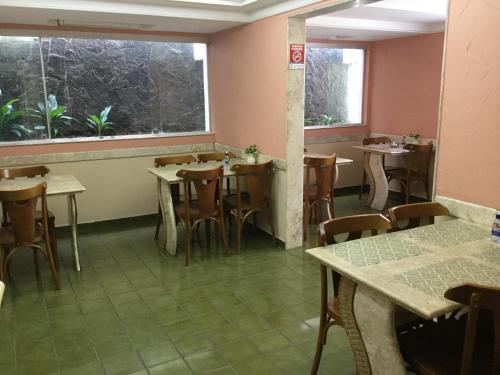 a restaurant with tables and chairs and a window at Hotel Porto Grande in Maceió