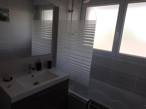 une salle de bain avec un lavabo, un miroir et une fenêtre dans l'établissement Villa proche plages, à Fouesnant