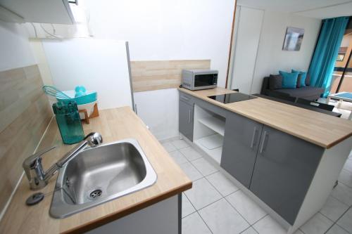 une cuisine avec un évier et un plan de travail dans l'établissement Front de Mer, au Barcarès