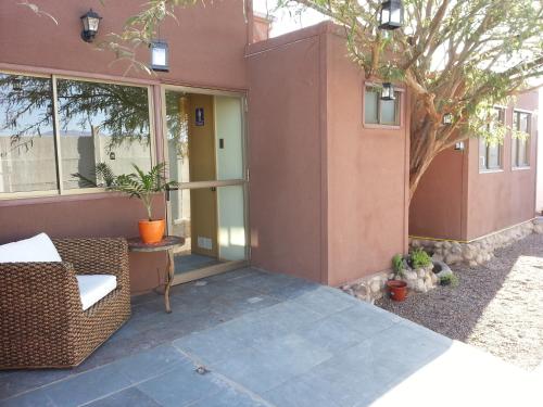 a porch of a house with a chair and a tree at Juku Hostal in Calama