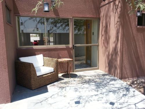 a patio with a chair and a table and windows at Juku Hostal in Calama