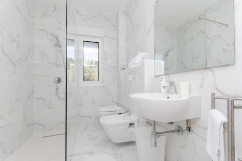 biała łazienka z toaletą i umywalką w obiekcie Apartments Branimir w mieście Mandre