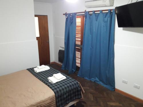 a bedroom with a bed with blue curtains and a tv at Departamento Maipú in Paraná