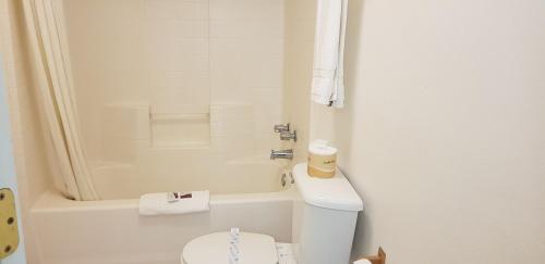 a white bathroom with a toilet and a tub at Night Inn in Globe