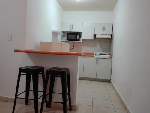 a kitchen with two bar stools and a microwave at MV Suites in Monterrey