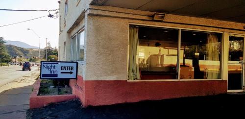 a sign on the side of a building with a wait sign in front at Night Inn in Globe