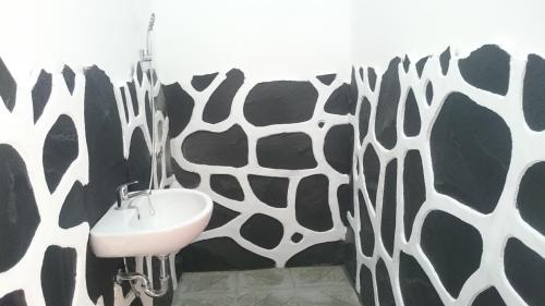 La salle de bains est pourvue d'un mur à motifs de vache noire et blanche. dans l'établissement Aryasuta Bungalow, à Tetebatu