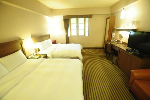 Habitación de hotel con 2 camas y TV de pantalla plana. en Kindness Hotel Taitung Branch en Taitung