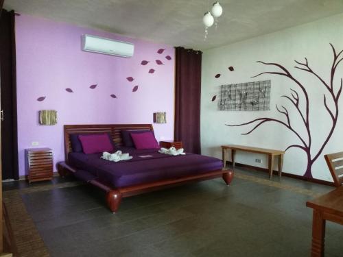 a bedroom with a purple bed and a tree mural at Punta Duarte Garden Inn in Los Duarte