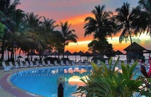 a resort swimming pool with a sunset in the background at Damai Beach Resort in Santubong