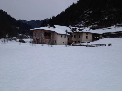 a building in a field covered in snow at Maso Toneto in Castello di Fiemme